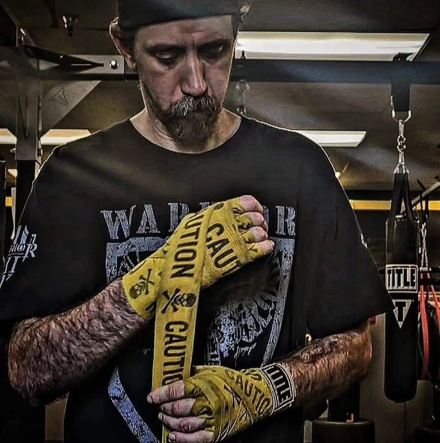 A fighter wrapping his hands in gold wraps inside the Our House Studios boxing room