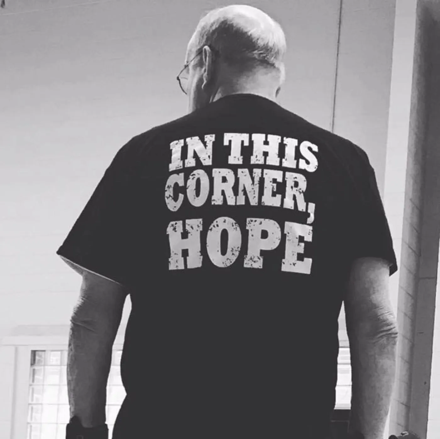 An older fighter from behind wearing a shirt that reads In This Corner, Hope